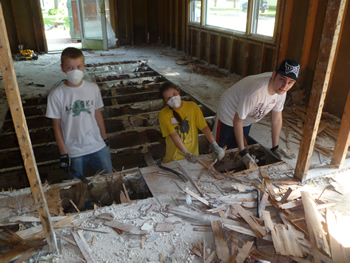 Haven King-Nobles, Teresa Jimenez Nickerson, and Scott Miller work to remove the flooring from a home slated for demolition.